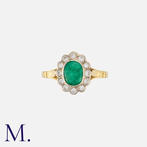 49 - An Emerald and Diamond Cluster Ring in 18K yellow and white gold set with an oval cut emerald to the... 