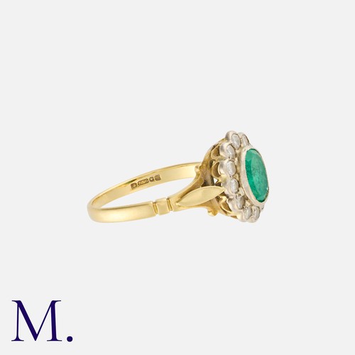 49 - An Emerald and Diamond Cluster Ring in 18K yellow and white gold set with an oval cut emerald to the... 