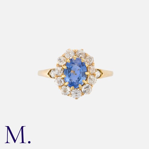 27 - A Sapphire And Diamond Cluster Ring in yellow gold, set with a principal oval cut sapphire of approx... 