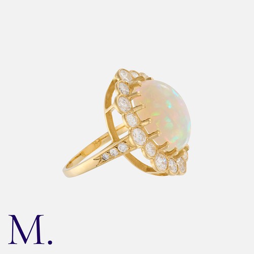 32 - An Opal And Diamond Cluster Ring in 18k yellow gold, set with a principal cabochon opal of approxima... 