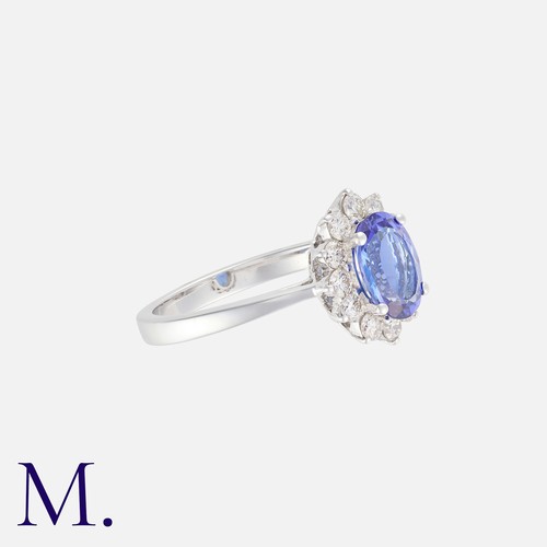 10 - A Tanzanite And Diamond Cluster Ring in 18k white gold, set centrally with an oval cut tanzanite of ... 