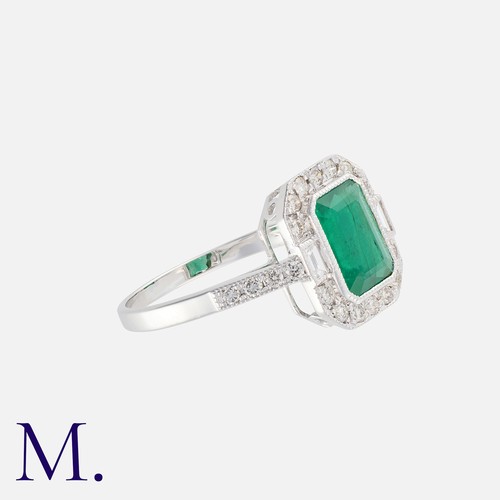 41 - An Emerald And Diamond Cluster Ring in 18k white gold, set with a principal octagonal cut emerald of... 