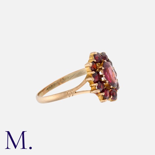 12 - A Garnet Cluster Ring in 9k yellow gold, set with an oval garnet in a border of round cut garnets. S... 