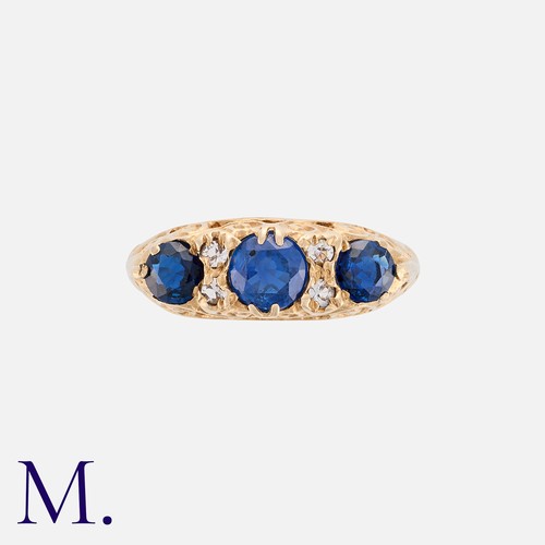 82 - A Sapphire And Diamond Ring in 9k yellow gold, comprising three round cut sapphire punctuated by pai... 