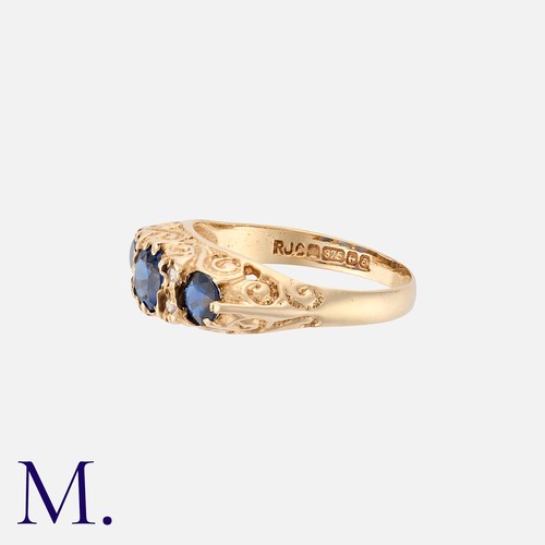 82 - A Sapphire And Diamond Ring in 9k yellow gold, comprising three round cut sapphire punctuated by pai... 