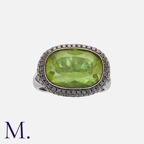 237 - A Peridot And Black Diamond Ring in 18k blackened gold. Set with a principal elongated cushion cut p... 