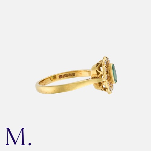 18 - An Emerald and Diamond Ring in 18K yellow gold, set with an oval cut emerald, with twelve round cut ... 