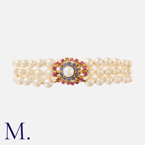 152 - A Pearl Bracelet in 18k yellow gold, comprising three strands of pearls terminating in a ruby, sapph... 