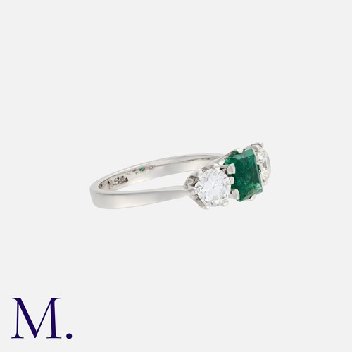 54 - An Emerald And Diamond Three Stone Ring in 18k white gold, set centrally with a step cut emerald of ... 