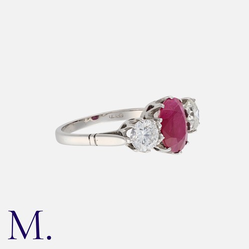 75 - A Ruby And Diamond Three Stone Ring in 18k white gold,  set centrally with an oval cut ruby of appro... 