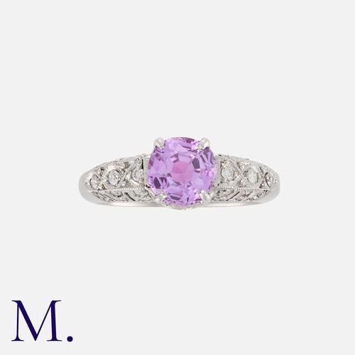 40 - A Pink Sapphire and Diamond Ring in platinum, set to the centre with a round cut sapphire weighing a... 