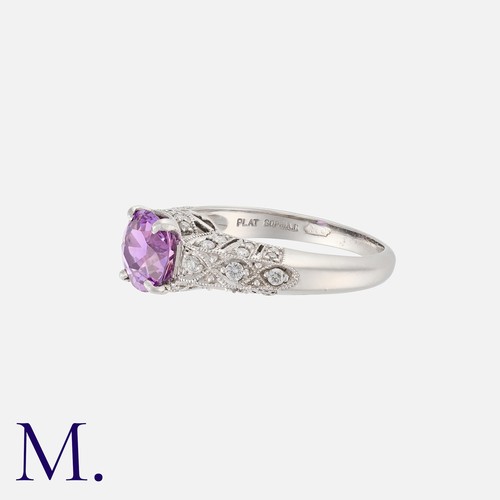 40 - A Pink Sapphire and Diamond Ring in platinum, set to the centre with a round cut sapphire weighing a... 