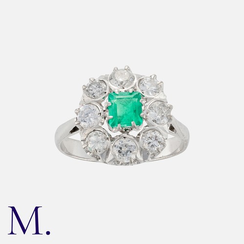 80 - An Emerald And Diamond Cluster Ring in 18k white gold, set centrally with a square cut emerald of ap... 