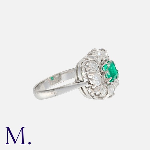 80 - An Emerald And Diamond Cluster Ring in 18k white gold, set centrally with a square cut emerald of ap... 