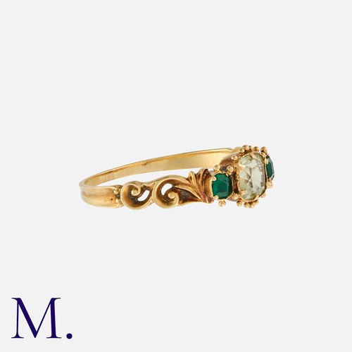 160 - A Chrysolite And Emerald Three Stone Ring in yellow gold, set with a central cushion cut chrysolite,... 