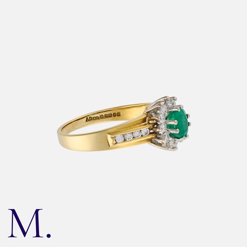 138 - An Emerald and Diamond Cluster Ring in 18K yellow and white gold, set with an oval cut emerald weigh... 