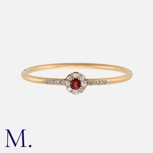 89 - A Garnet and Diamond Bangle in 18K yellow gold, with a round cut garnet with rose cut diamonds in su... 