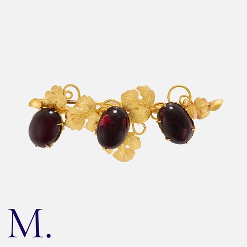 69 - A Garnet Brooch in yellow gold, of foliate design, with ornate detailed leaves, accented by three ca... 