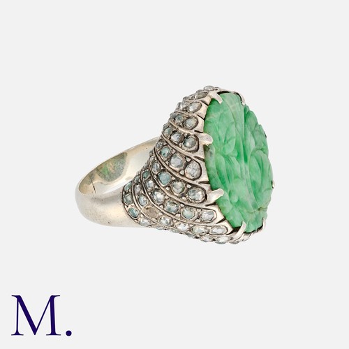 143 - A Jade And Diamond Ring, set with a floral carved piece of jade, to a rose cut diamond set mount. Un... 