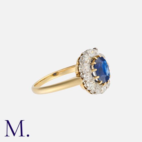 38 - A Sapphire And Diamond Cluster Ring in yellow gold, set with a principal cushion cut sapphire of app... 