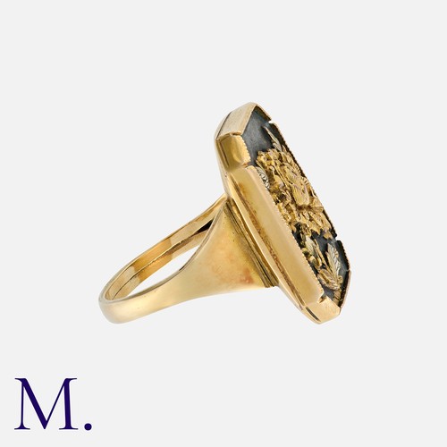 84 - A Shakudo Ring in yellow gold, set with an octagonal plaque featuring a high relief engraved floral ... 