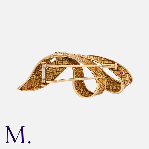 48 - BOUCHERON. A Ruby Clip Brooch in 18K yellow gold in the form of a flowing, textured ribbon set with ... 