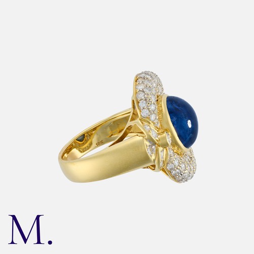 151 - A Sapphire And Diamond Cluster Ring in 18k yellow gold, set with a principal oval cabochon sapphire ... 