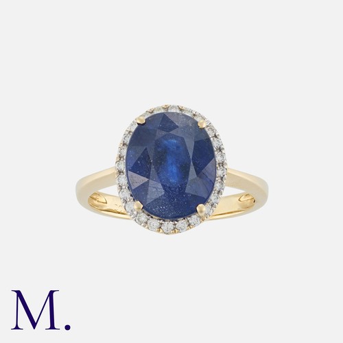 129 - A Sapphire And Diamond Cluster Ring in 14k yellow gold, set with a principal oval cut sapphire of ap... 