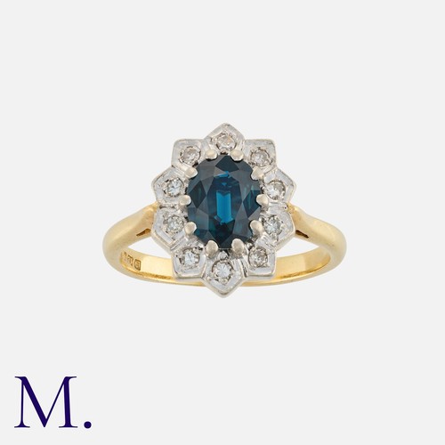 73 - A Sapphire And Diamond Cluster Ring in 18k yellow gold, set with a central oval cut sapphire within ... 