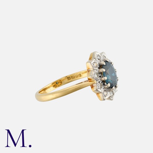 73 - A Sapphire And Diamond Cluster Ring in 18k yellow gold, set with a central oval cut sapphire within ... 