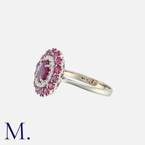 105 - A Ruby And Diamond Cluster Ring in 18k white gold, set with a central cushion cut ruby of approximat... 