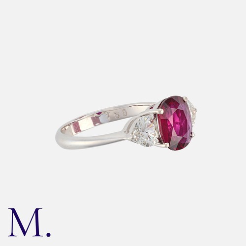 169 - A Ruby And Diamond Three Stone Ring in platinum, set with a central cushion cut ruby of approximatel... 
