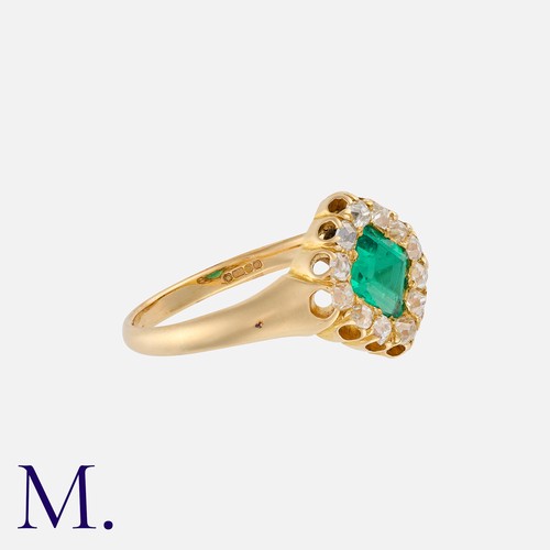 136 - An Emerald And Diamond Cluster Ring in 18k yellow gold, set centrally with a square shaped emerald o... 