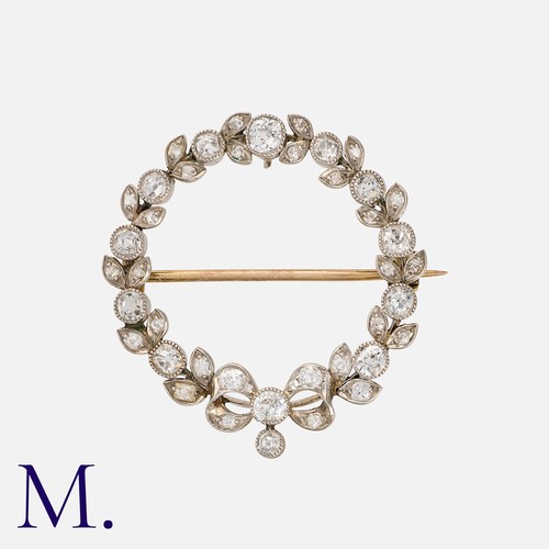 147 - A Diamond Brooch in yellow gold and platinum, of wreath form, with bow motif to the age, set with ol... 