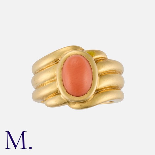 130 - VAN CLEEF & ARPELS. A Coral Ring in 18K yellow gold, set with a cabochon onyx to the centre with flu... 