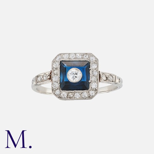 98 - An Art Deco Sapphire and Diamond Cluster Ring in platinum, comprising a drilled square cut sapphire,... 