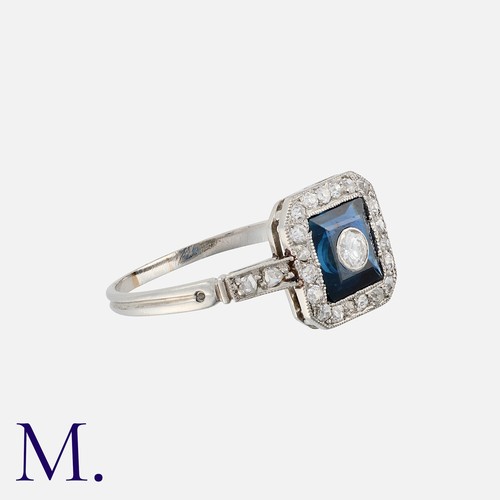 98 - An Art Deco Sapphire and Diamond Cluster Ring in platinum, comprising a drilled square cut sapphire,... 
