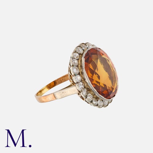 12 - A Citrine and Diamond Cluster Ring in yellow gold and silver, set with an oval cut citrine within a ... 