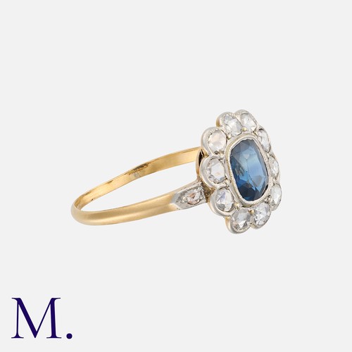 24 - A Sapphire and Diamond Cluster Ring in yellow gold, set with an oval cut blue sapphire to the centre... 