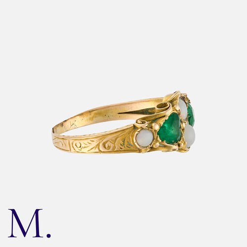 102 - An Emerald and Opal Ring in yellow gold, set with cabochon opals and two emeralds to an ornate band.... 