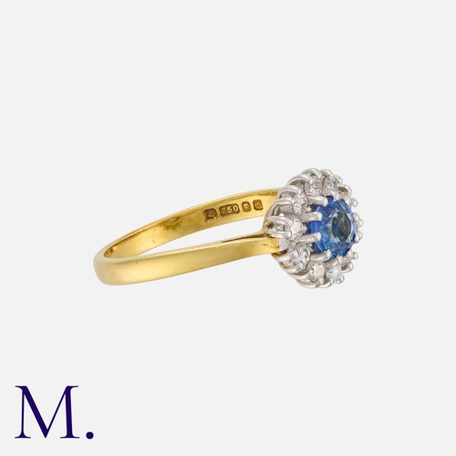 13 - A Sapphire and Diamond Cluster Ring in 18 carat gold, set with a principal round cut sapphire within... 