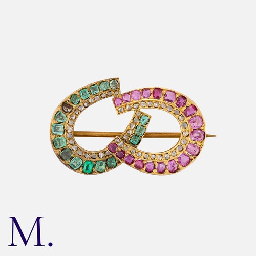 139 - An Antique Ruby, Emerald and Diamond Brooch in yellow gold. Designed as two horse shoes, one set wit... 