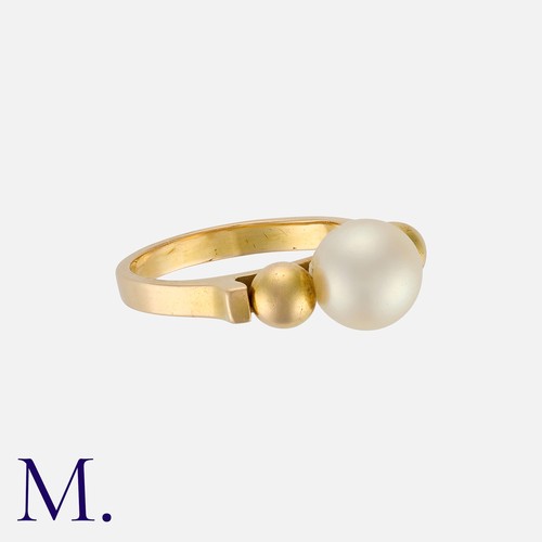 4 - JEAN DESPRÈS. A Pearl Ring in 18K yellow gold with a cream pearl set to the centre of two gold balls... 