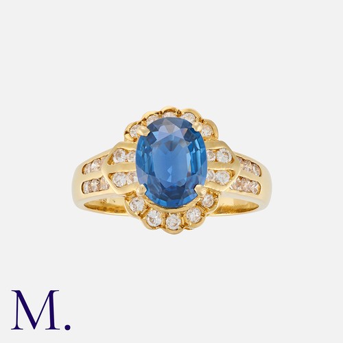 87 - A Sapphire and Diamond Cluster Ring in 18K yellow gold, set with an oval cut sapphire weighing appro... 