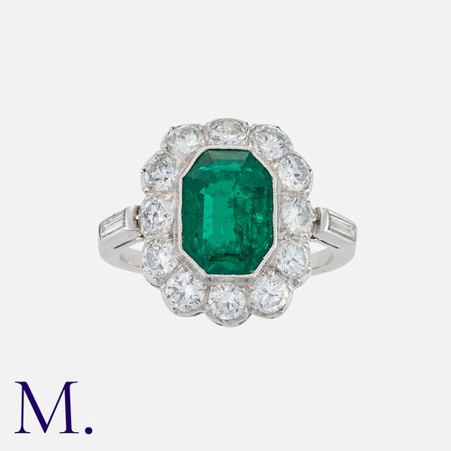 113 - A Colombian Emerald and Diamond Cluster Ring in platinum, set with a principal octagonal step cut em... 