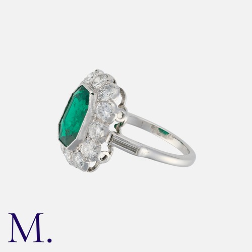 113 - A Colombian Emerald and Diamond Cluster Ring in platinum, set with a principal octagonal step cut em... 