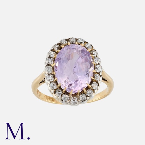 83 - A Pink Sapphire And Diamond Cluster Ring in yellow gold, set with a principal oval cut sapphire of a... 