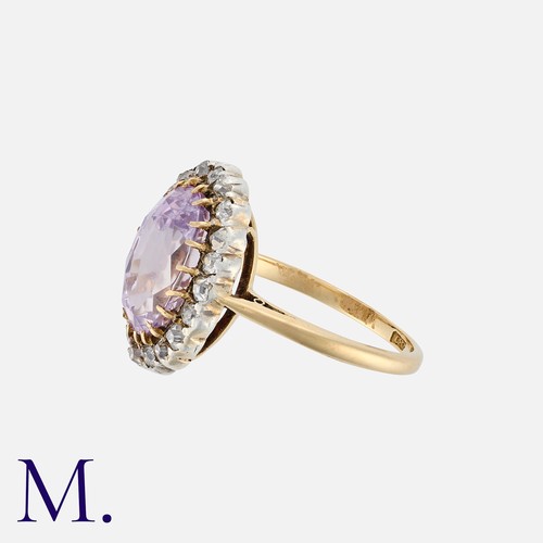 83 - A Pink Sapphire And Diamond Cluster Ring in yellow gold, set with a principal oval cut sapphire of a... 