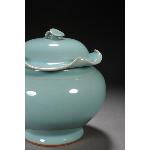 202 - A celadon glaced 'lotus' jar and cover 18cm high, 17cm wide