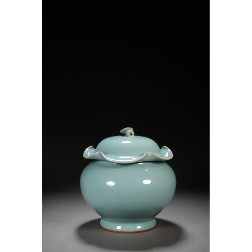 202 - A celadon glaced 'lotus' jar and cover 18cm high, 17cm wide